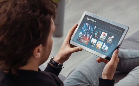 mains qui tiennent une tablette donnant sur un video store